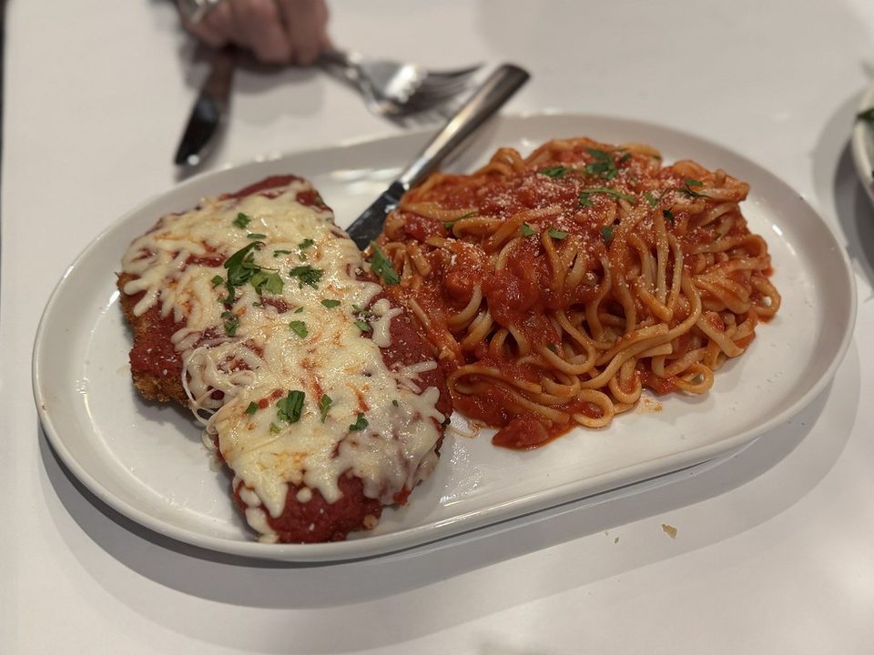 Breaded chicken parmesan with melted mozzarella next to a nest of spaghetti in marinara