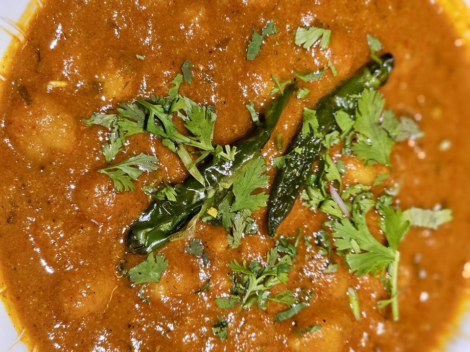 Bowl of chickpea curry in a rich tomato sauce garnished with cilantro