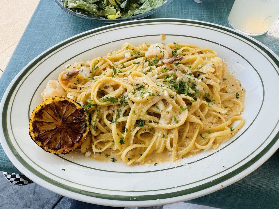 Shrimp linguine with parsley and a grilled lemon half on a white plate