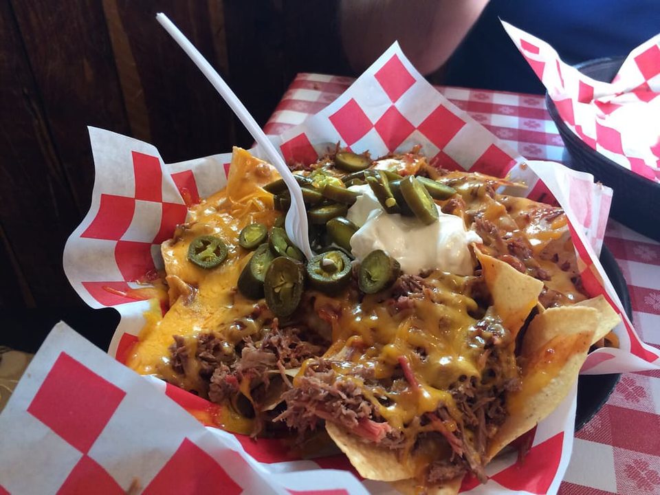 Nachos loaded with melted cheese, shredded meat, jalapenos and sour cream in a paper-lined basket